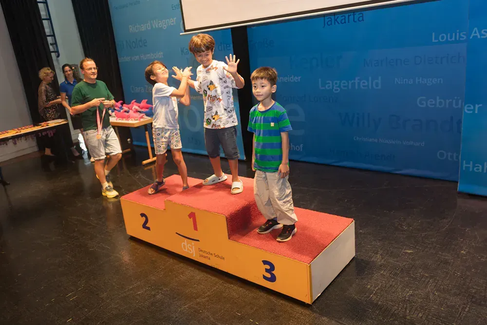Three young boys are standing on a podium with the numbers 1 2 and 3 on it