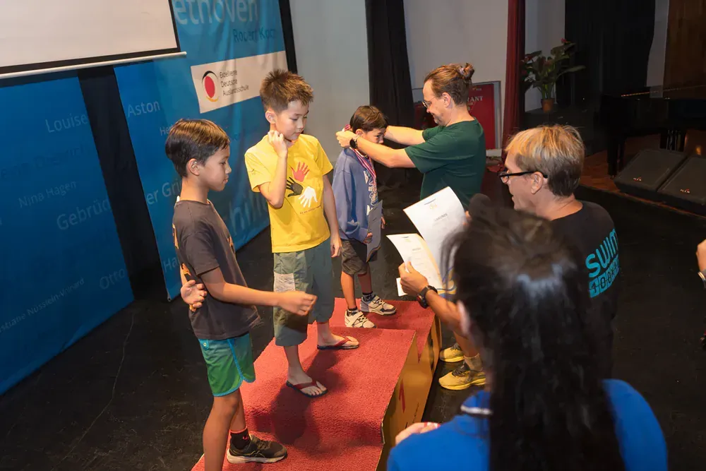 A woman is putting a medal on a boy 's neck.