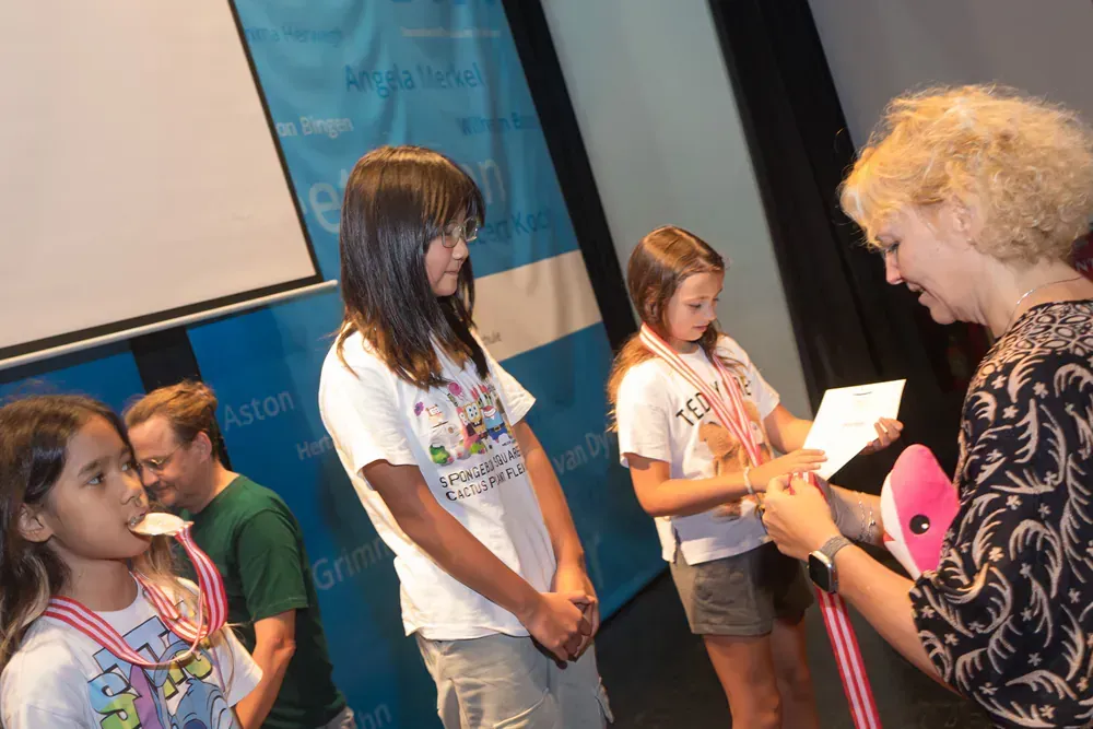 A woman is giving a medal to a group of young girls