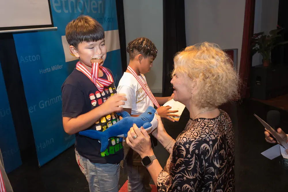 A woman is putting a medal on a child 's neck.