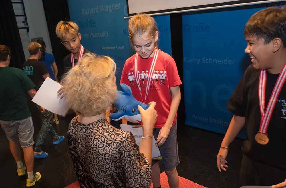 A woman is giving a medal to a young boy