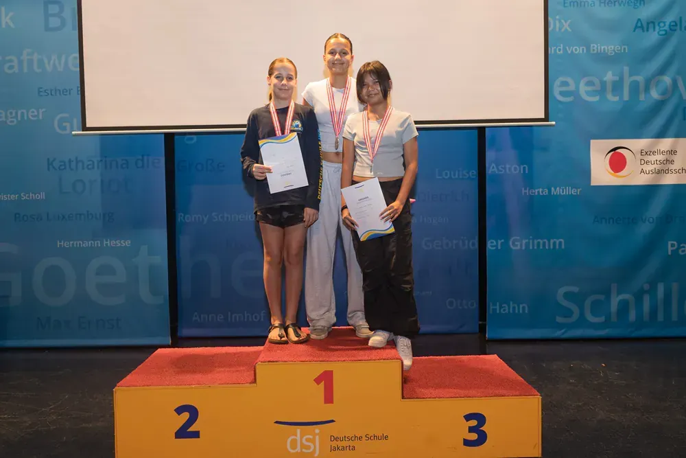 Three women are standing on a podium with the number 1 on it