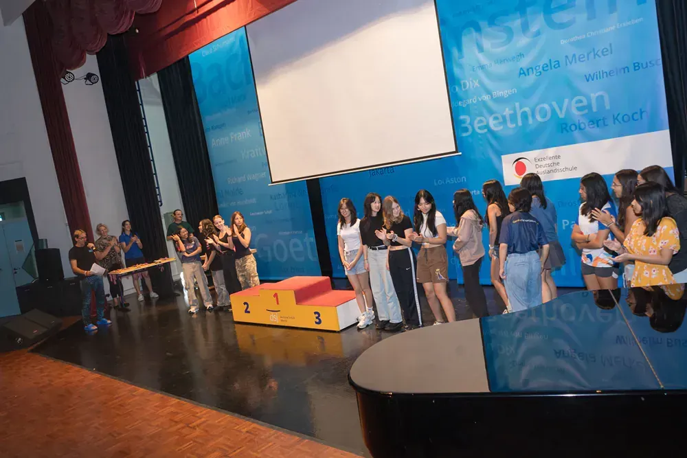 A group of people are standing on a stage in front of a large screen.