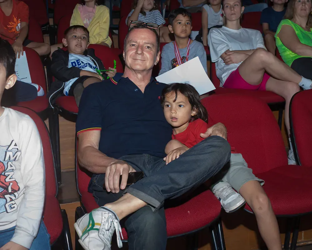 A man is holding a little girl while sitting in a theatre