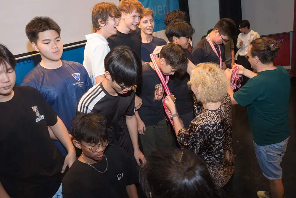 A group of young people are standing around a woman.