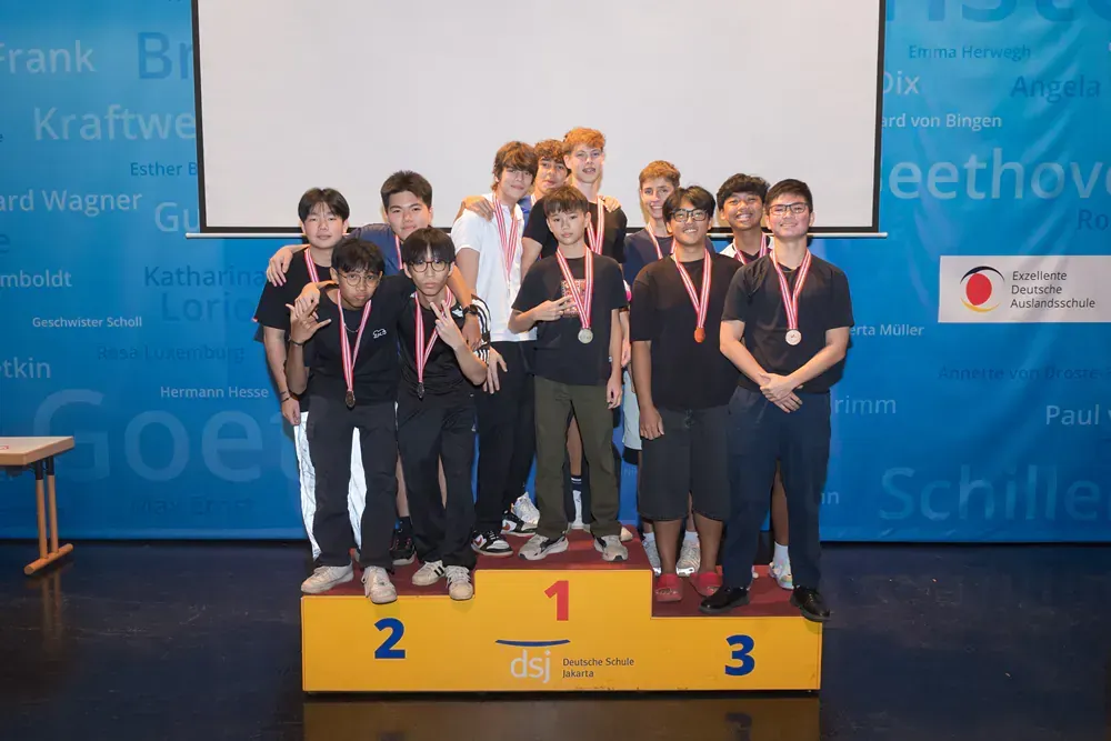 A group of young men are standing on a podium with medals around their necks.