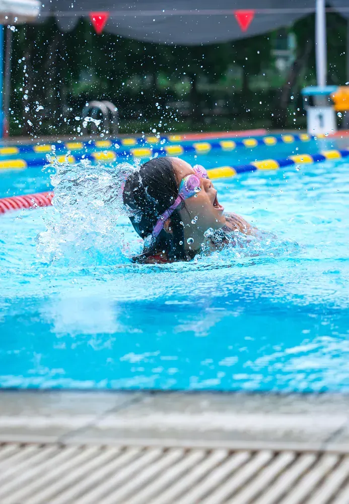 A woman is swimming in a swimming pool wearing goggles.