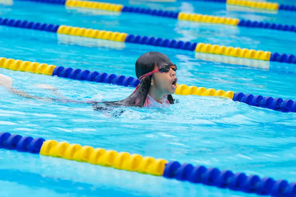 A young girl is swimming in a swimming pool.