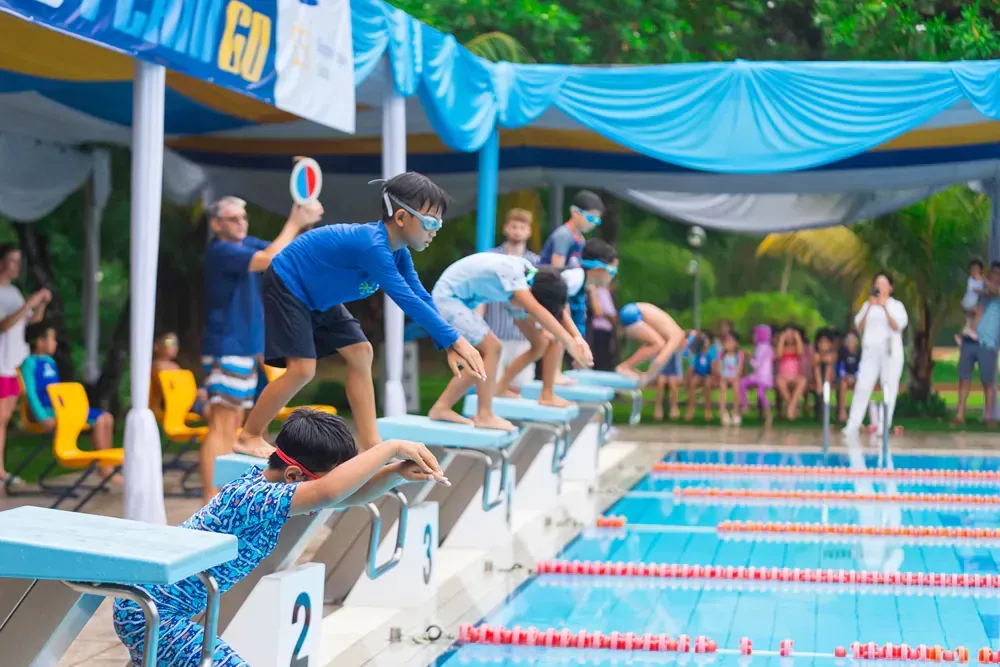 A group of children are jumping into a swimming pool.