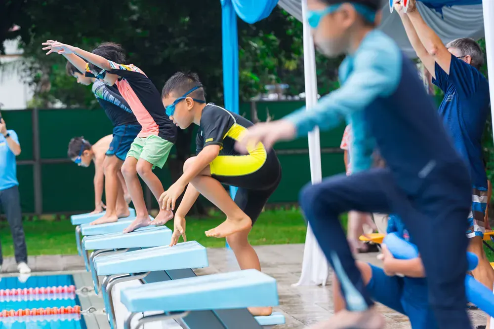 A group of young boys are jumping into a swimming pool.