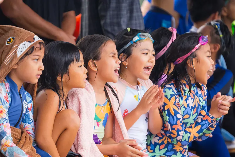 A group of young girls are sitting next to each other and clapping.