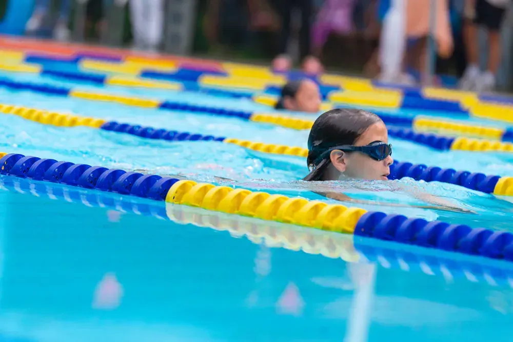 A woman is swimming in a swimming pool wearing goggles.