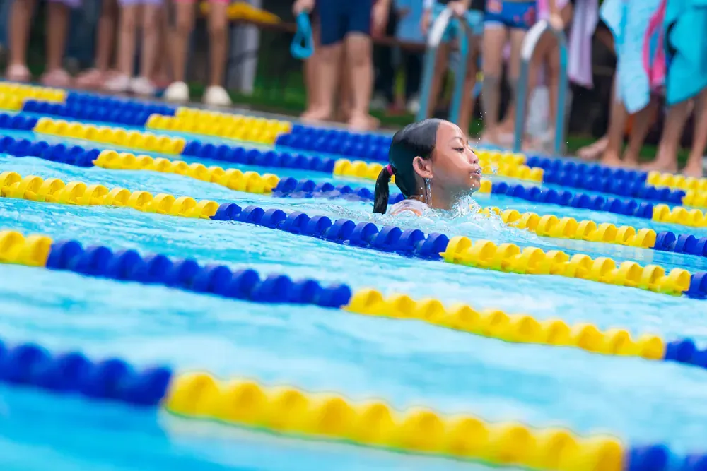 A young girl is swimming in a swimming pool.