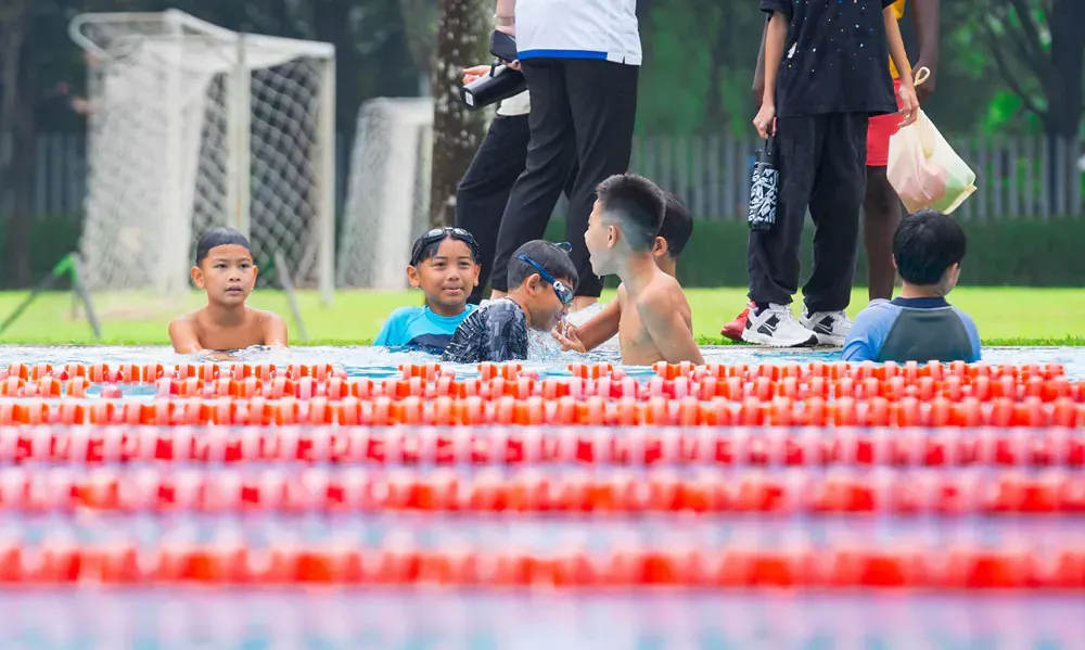 A group of children are swimming in a swimming pool.