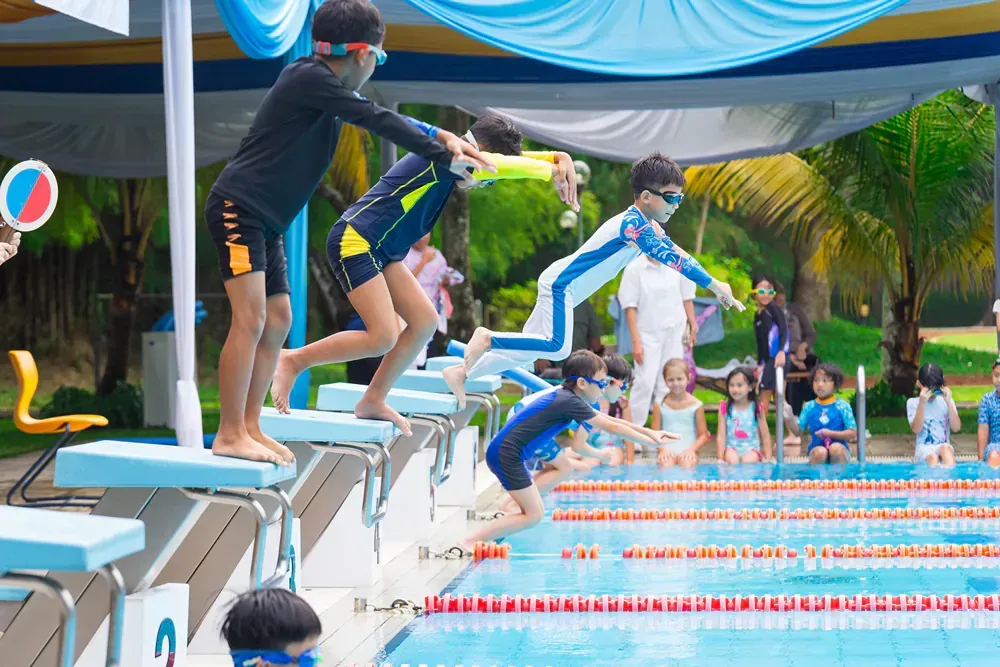 A group of children are jumping into a swimming pool.