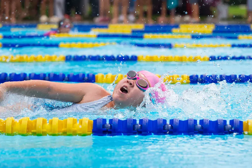 A young girl is swimming in a swimming pool.