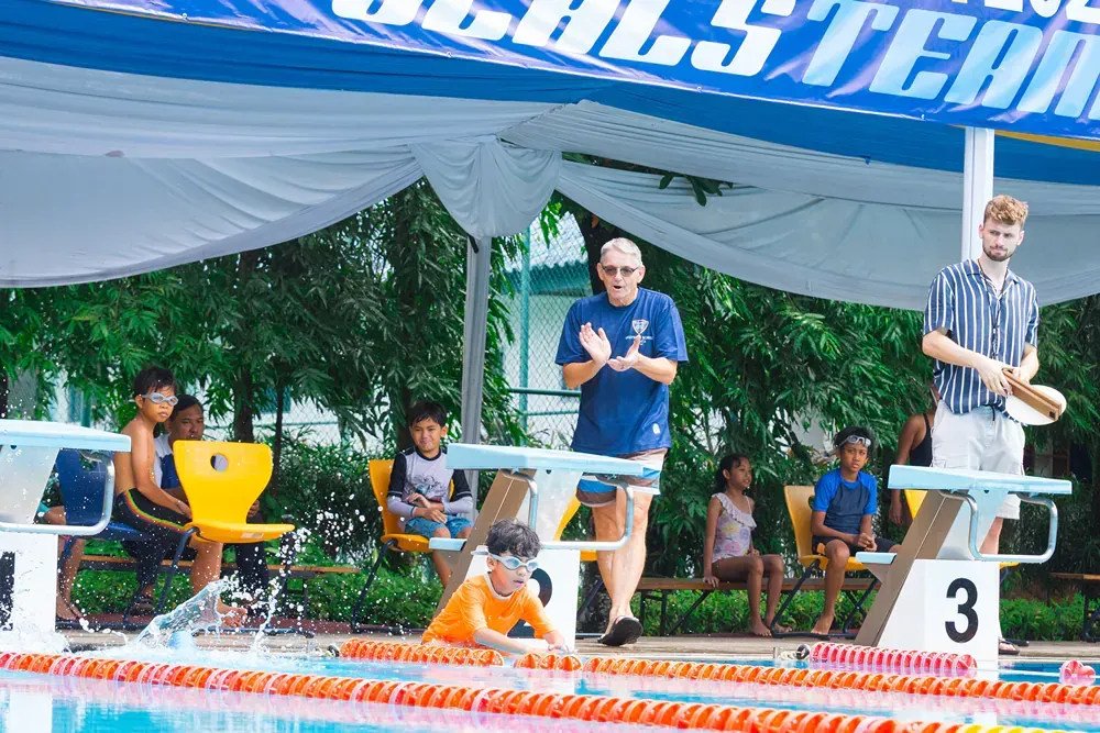 A group of people are standing around a swimming pool.