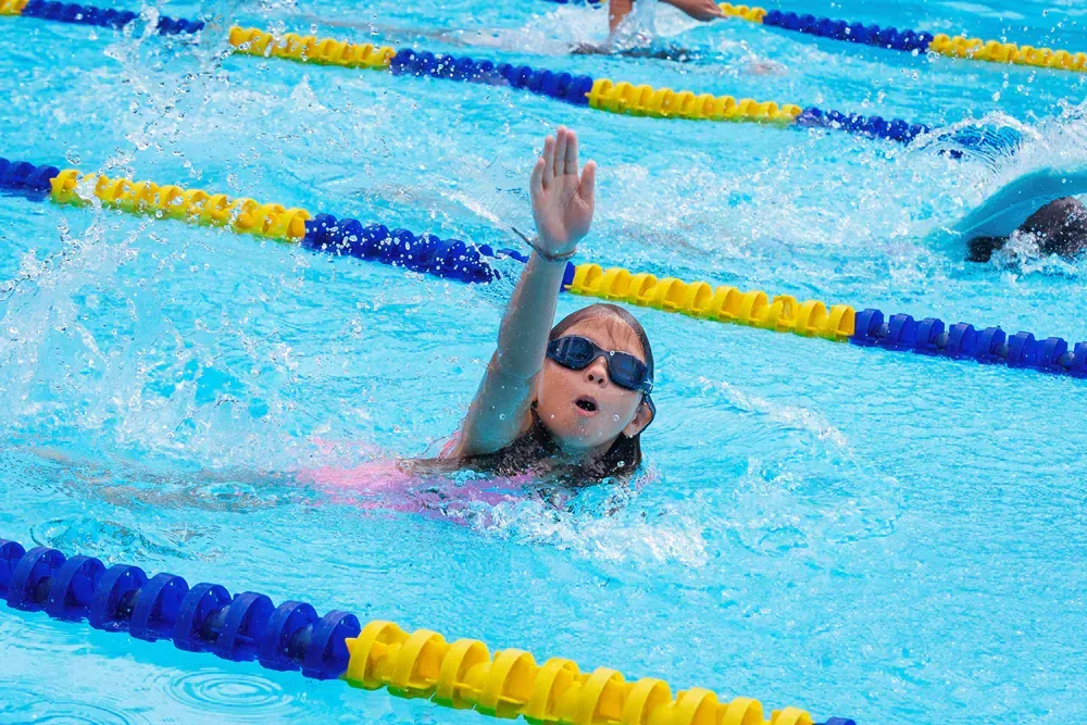 A young girl is swimming in a swimming pool.