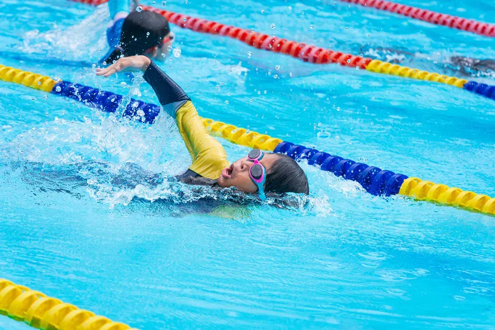 A group of people are swimming in a swimming pool.