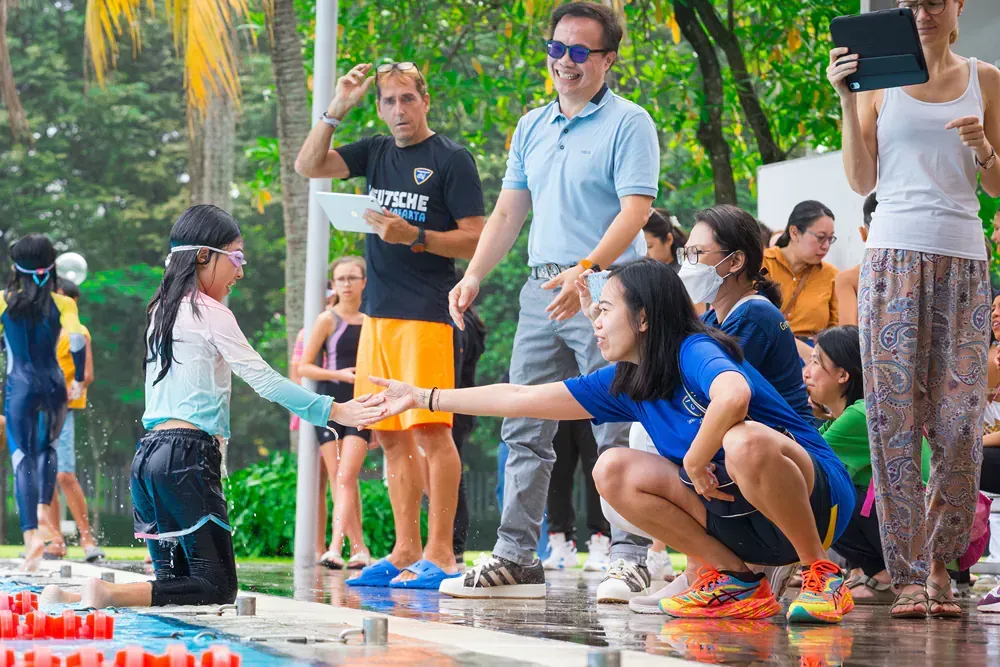A group of people are standing around a swimming pool.