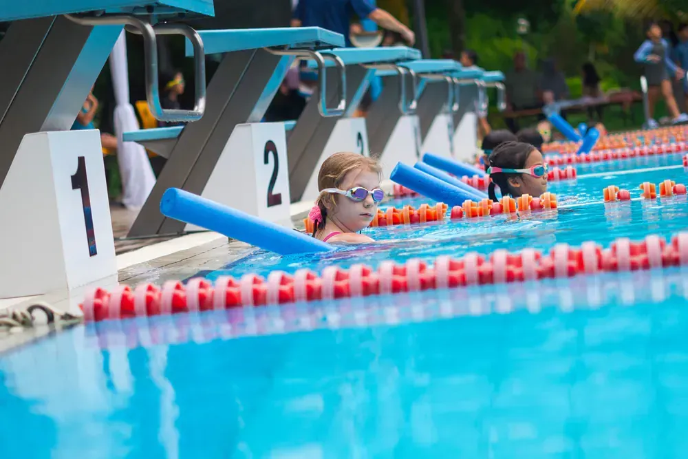 A group of children are swimming in a swimming pool.