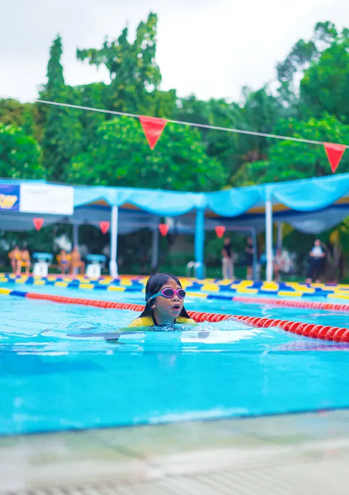 A young girl is swimming in a swimming pool.