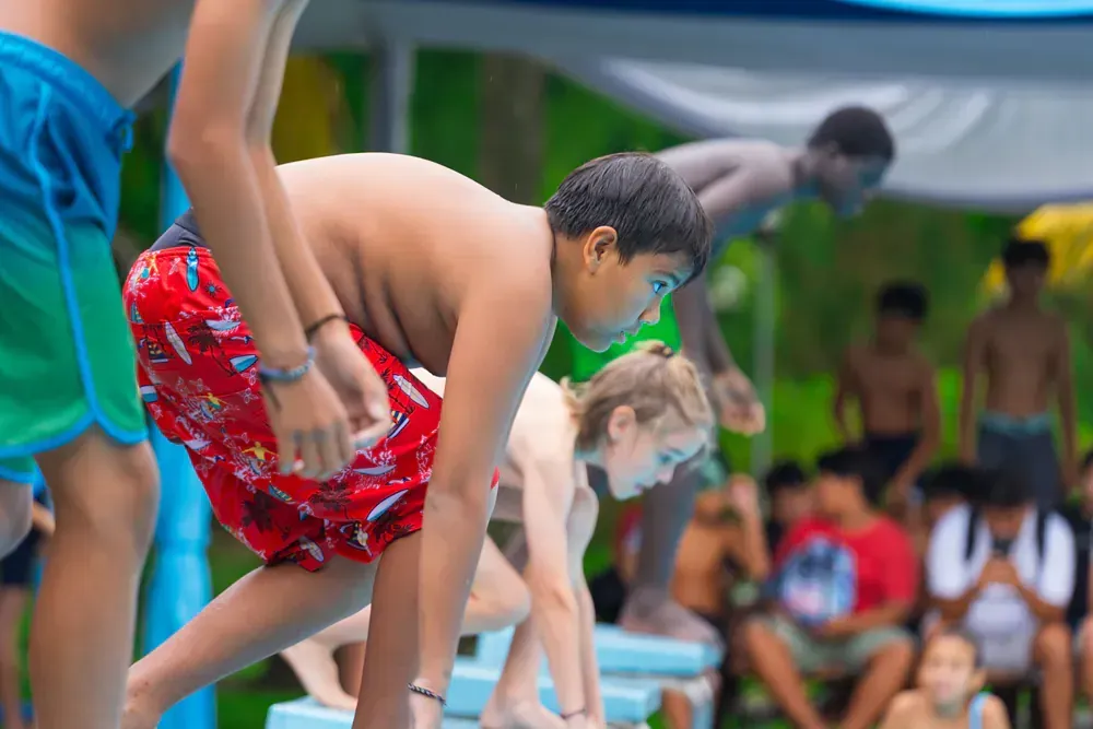 A group of young boys are getting ready to jump into a swimming pool.