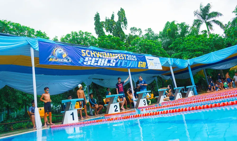 A group of people are standing around a swimming pool.