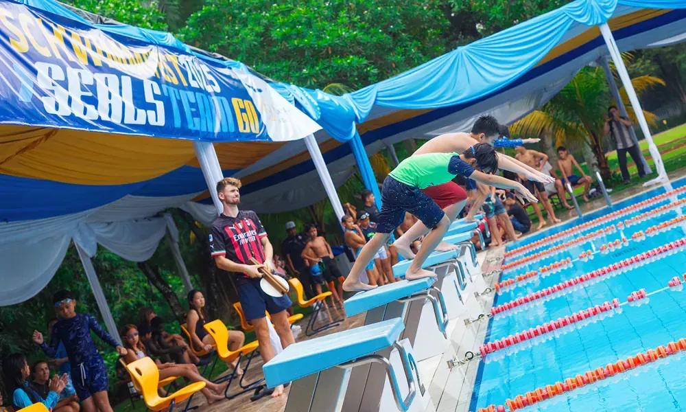 A group of people are jumping into a swimming pool.