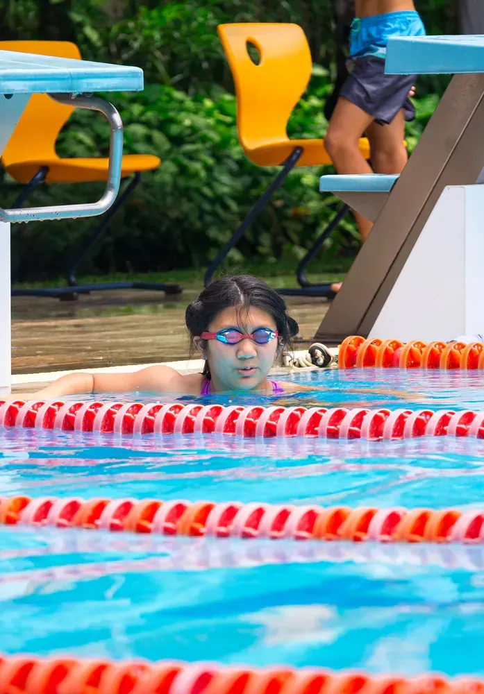A young girl is swimming in a pool wearing goggles.
