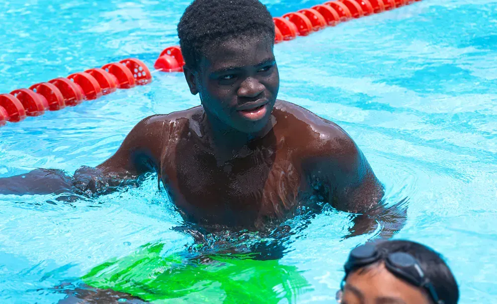 A man is swimming in a pool with a child.
