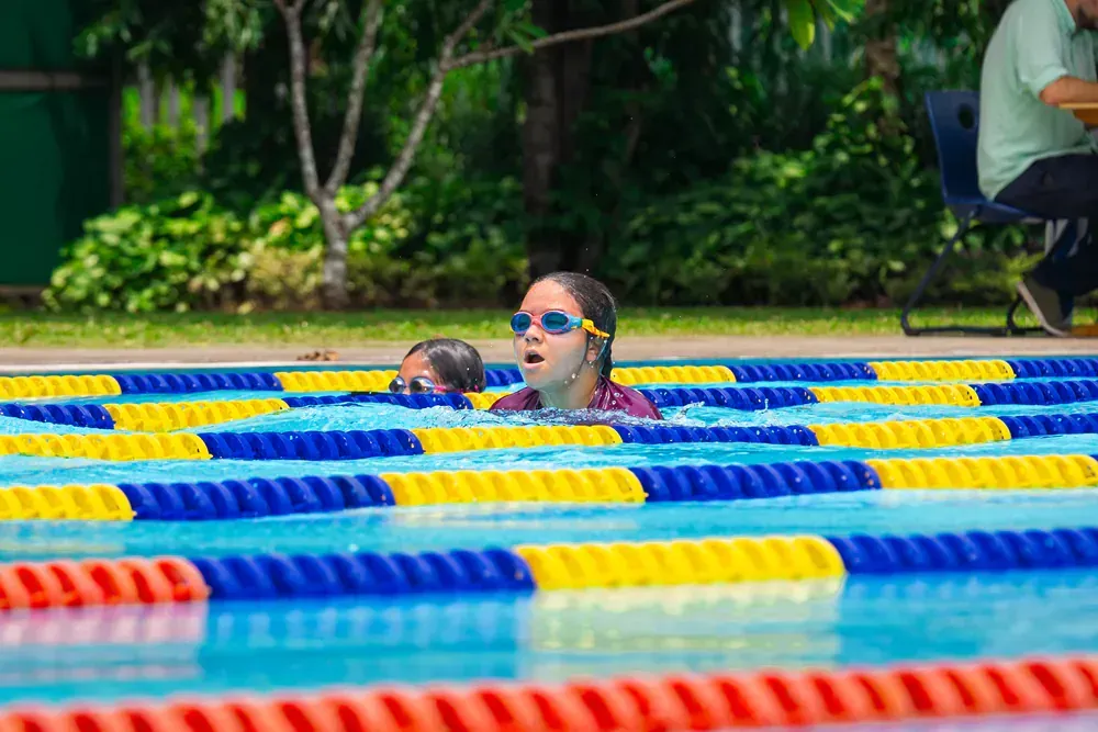 A woman is swimming in a swimming pool wearing goggles.