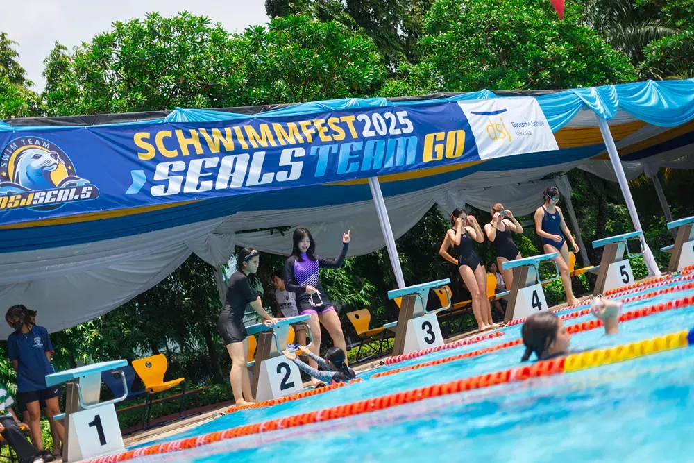 A group of people are standing on the edge of a swimming pool.