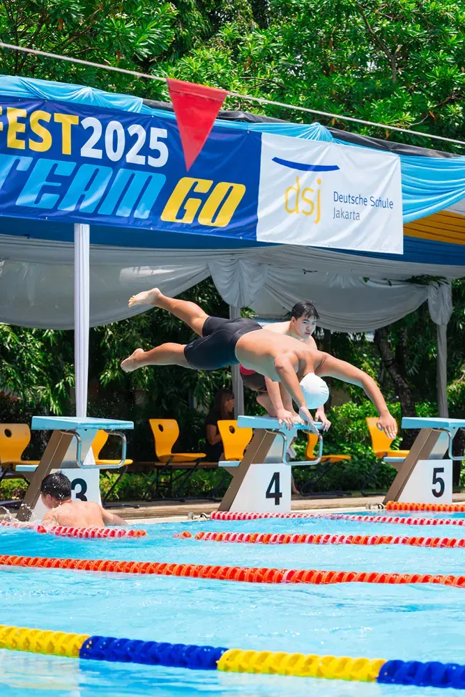 A man is diving into a swimming pool under a sign that says est 2025 team go.