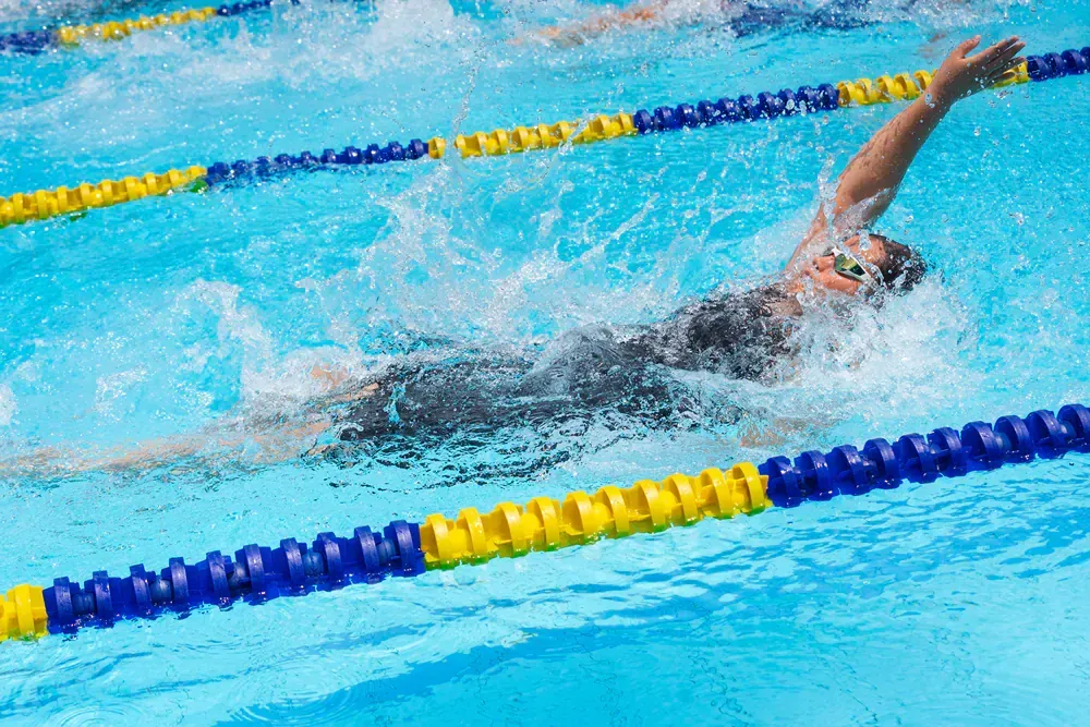 A woman is swimming in a swimming pool.