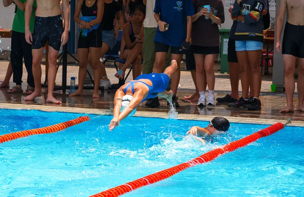 A group of people are watching a swimming competition in a pool.