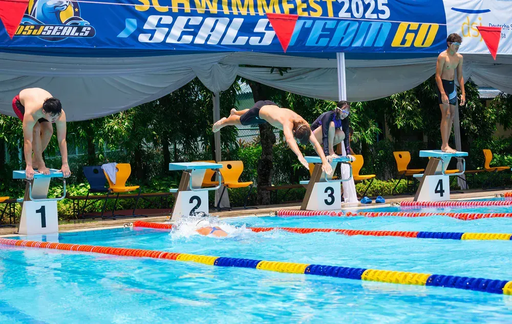 A group of people are jumping into a swimming pool.