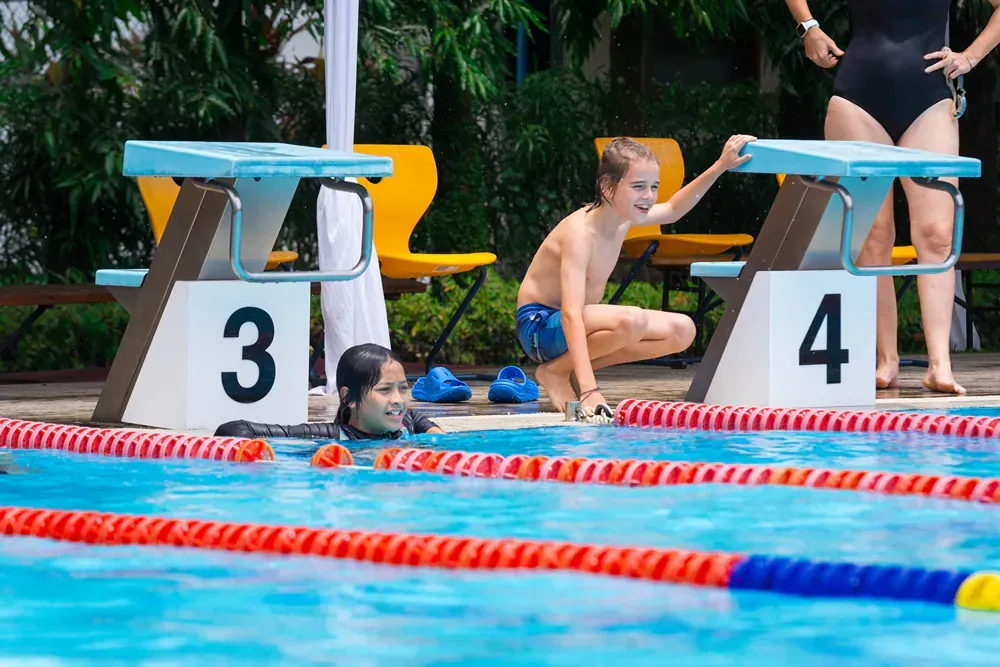 A group of people are swimming in a swimming pool.