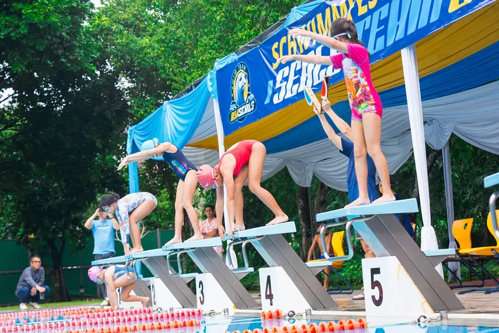 A group of young girls are getting ready to jump into a swimming pool.