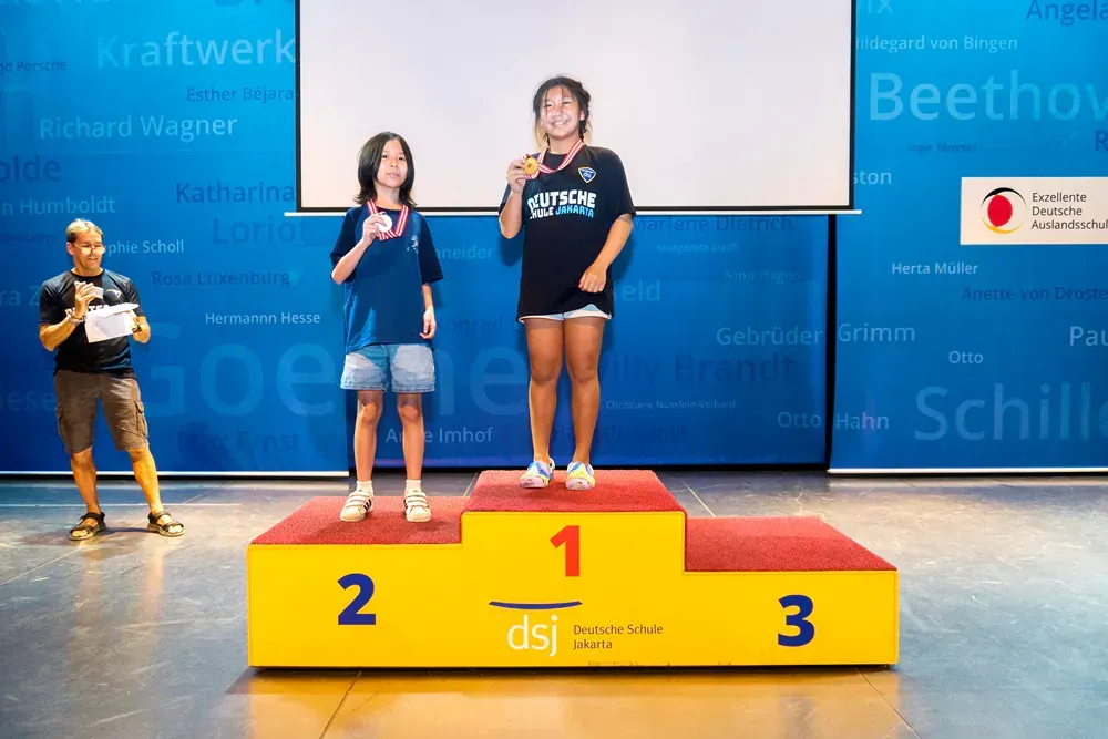 Three girls are standing on a podium with the number 1 2 and 3 on it.