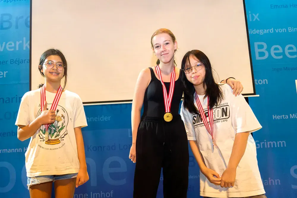 Three girls are posing for a picture with medals around their necks