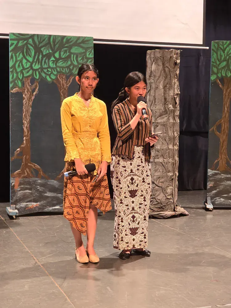 Two women are standing next to each other on a stage holding microphones.