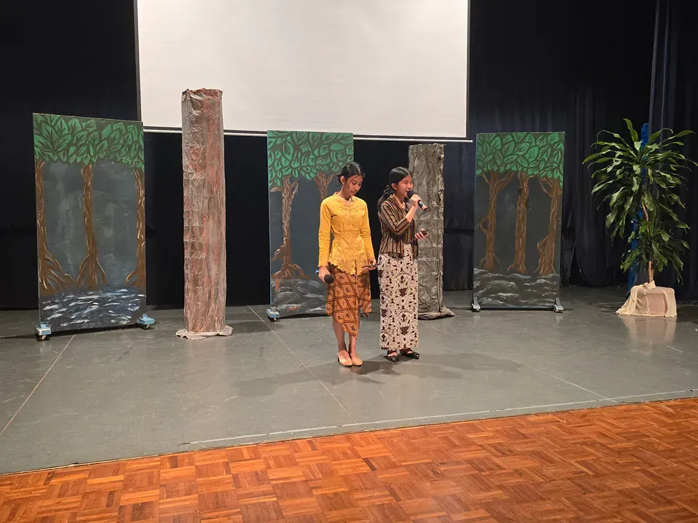 Two women are standing on a stage talking into microphones.