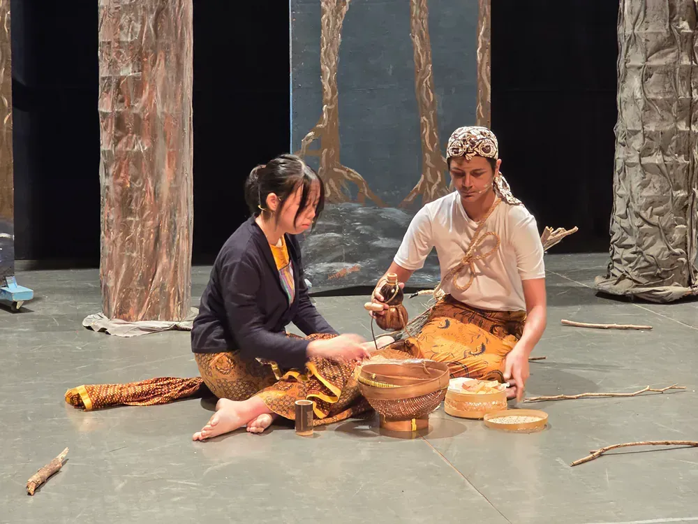 A man and a woman are sitting on the floor playing instruments.