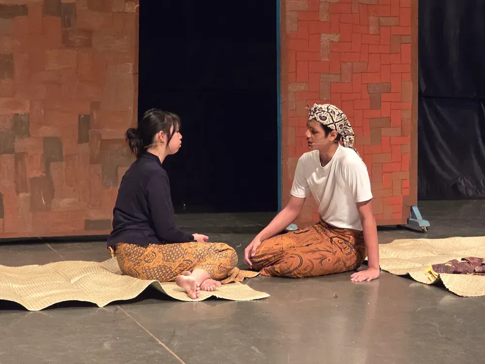 Two women are sitting on the floor talking to each other.