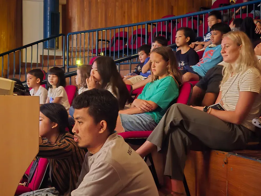 A group of people are sitting in an auditorium watching a presentation
