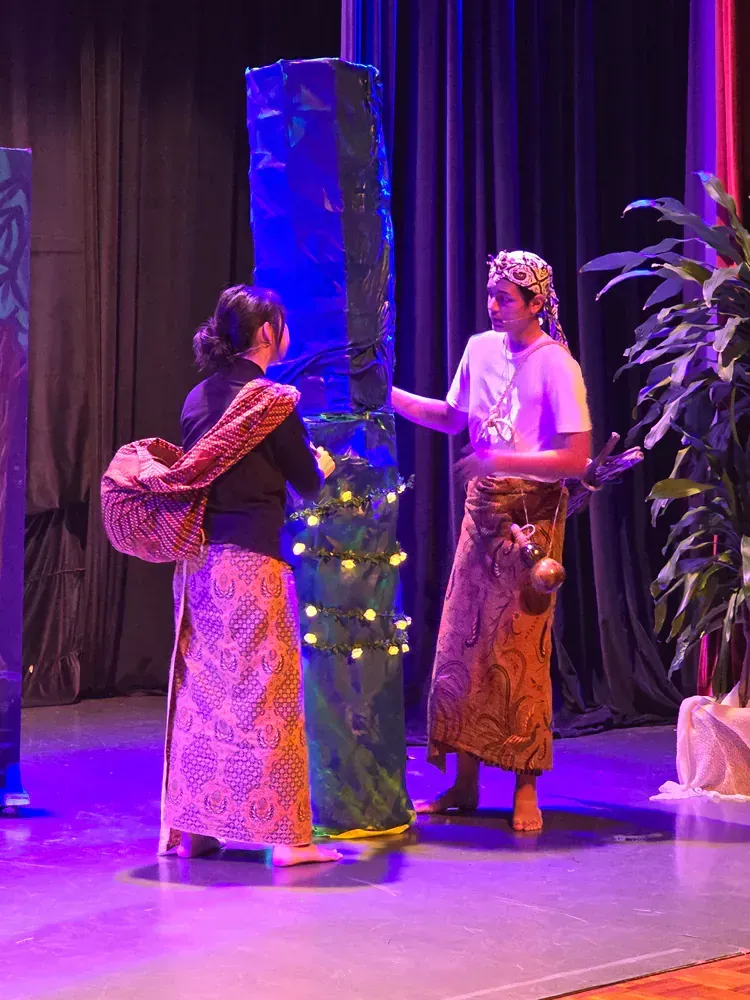 A man and a woman are standing on a stage talking to each other.