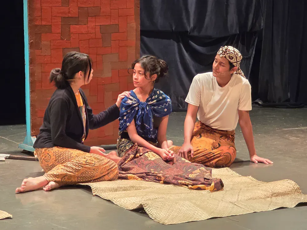 A group of people are sitting on the floor on a stage.