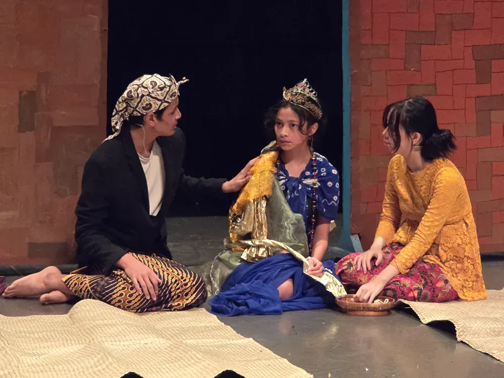 A man and two women are sitting on the floor talking to each other.