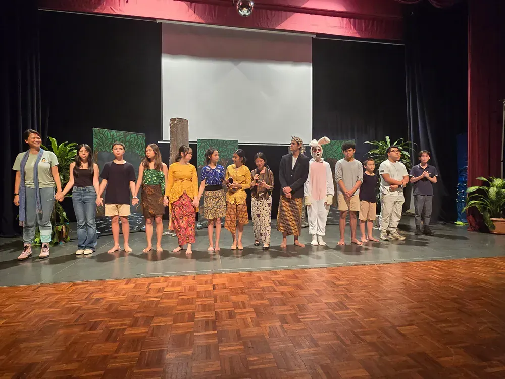 A group of people are standing on a stage holding hands.